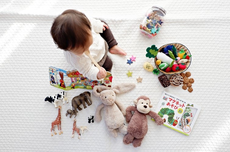 A baby sits with toys and books