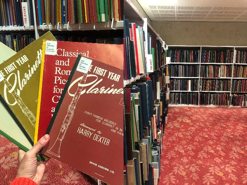 A composite image of two photos - one of a hand holding some vintage music books and the other showing stacks in a library