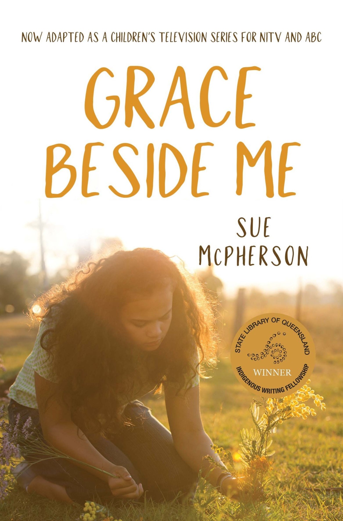 The cover of 'Grace beside me' showing a girl kneeling at sunset laying flowers on the grass