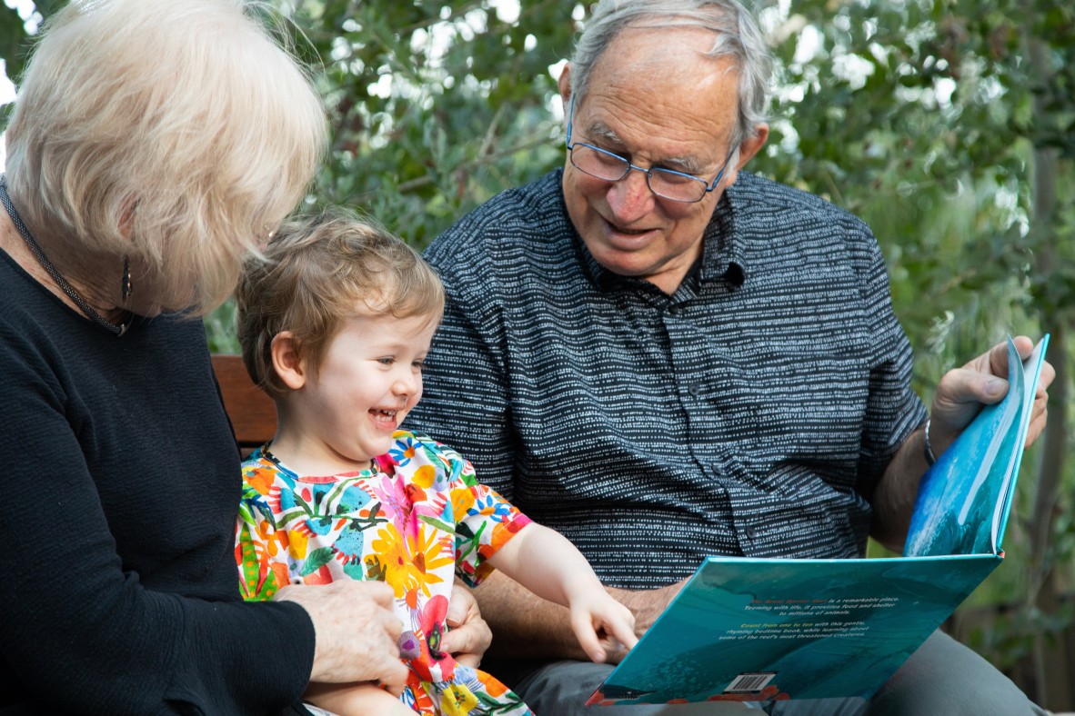 Child smiling as her grandparents read her a story