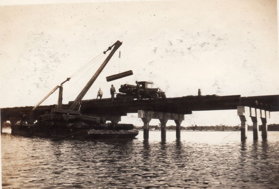 Girder supplies being loaded from a barge to be placed between the spans on the Bridge 1752 girders were used all 30 lengths They were shipped down river by barge after coming by rail from the mills at Conondale or Mapleton