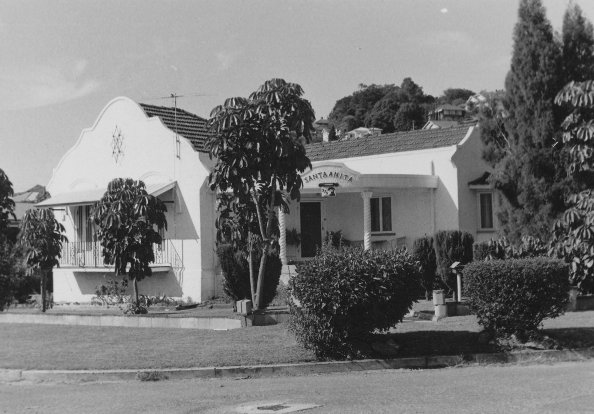 A white house with curved edges and trees in the front yard