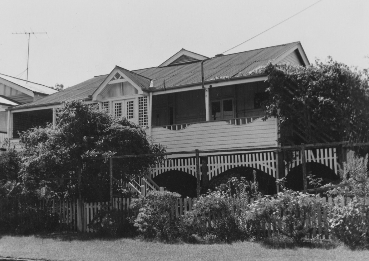 A multi gable house with lots of shrubs at the front