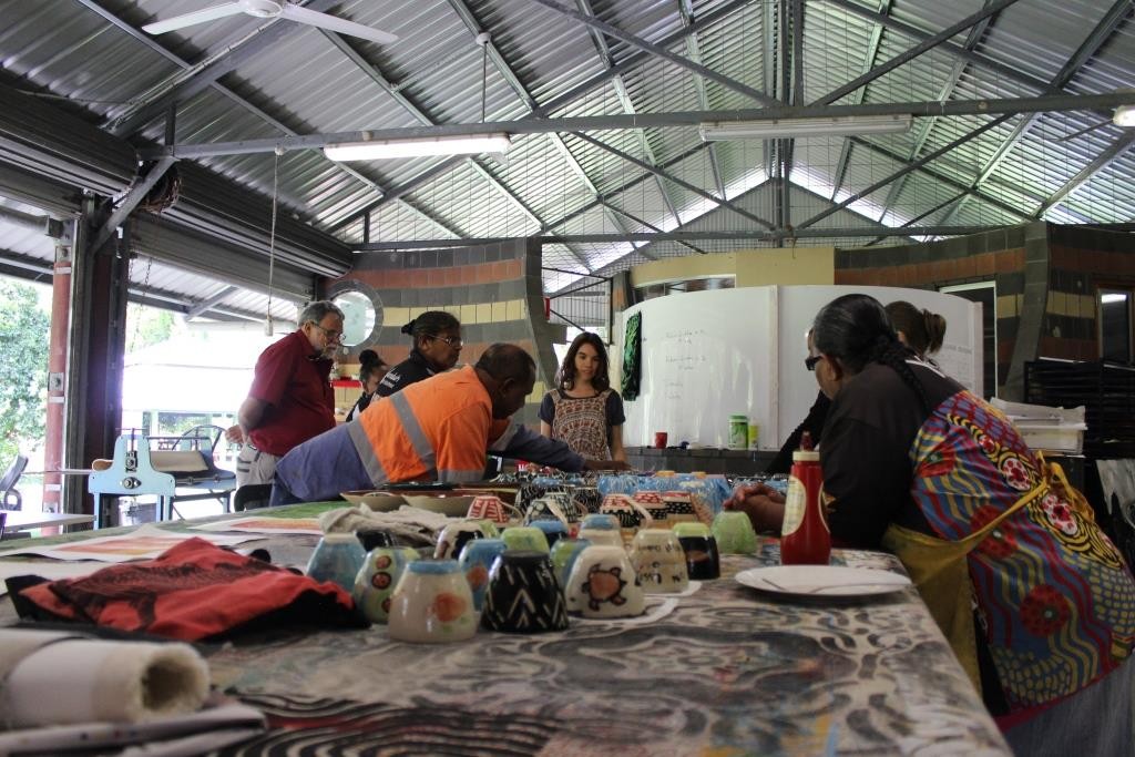 Group looking at painted ceramics around a table