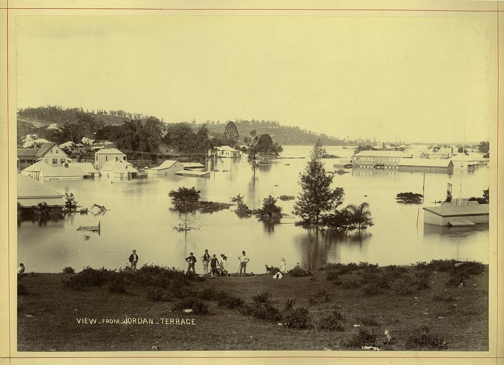 people stand on a hill overlooking flood waters 