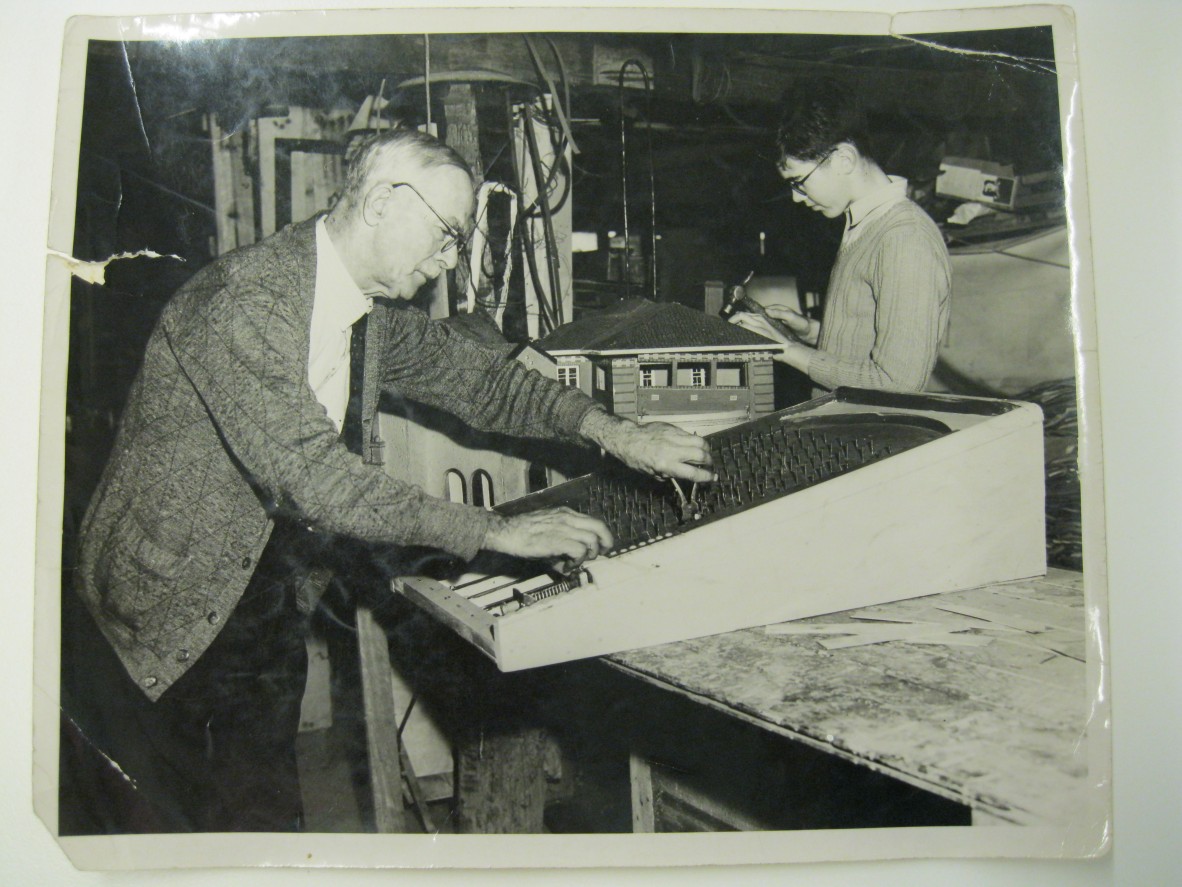 An older man using hand tools at workbench to make a bagatelle game