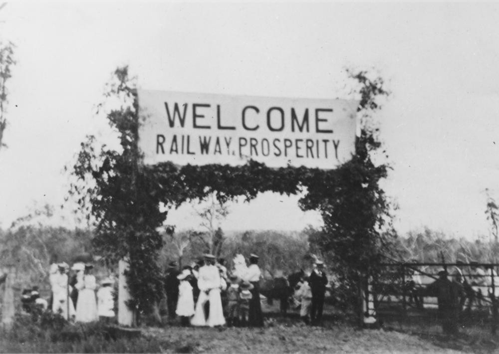 Group of people standing under a welcome sign at Kingaroy railway station 1904.