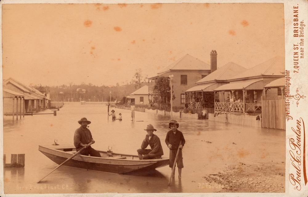 men row a boat in a flooded street
