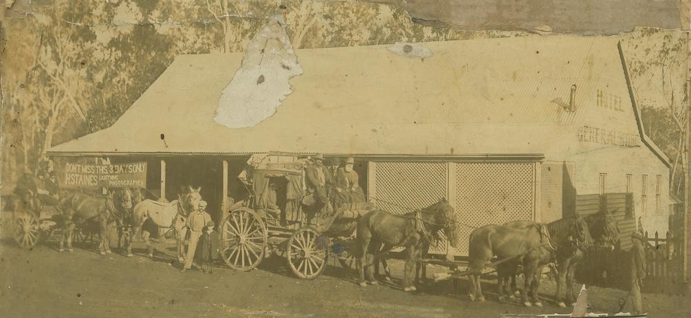 sepia toned image of two horse and carts outside a white building 