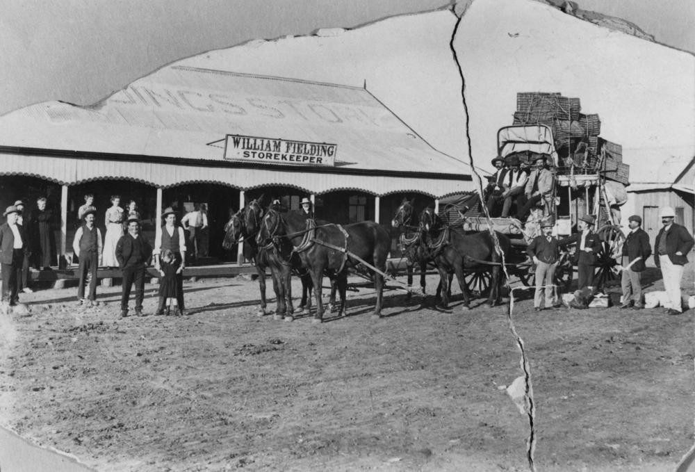 horse drawn cart with people standing next to it beside a building named the William fielding storekeeper