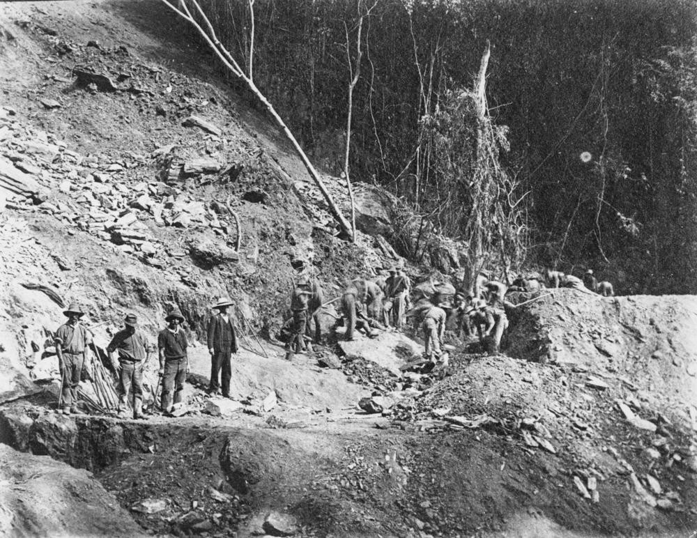 men stand on an dirt embankment while constructing railway 