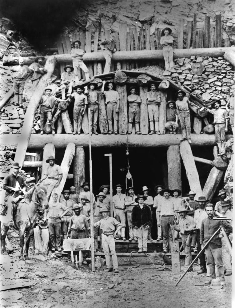 large group of workmen pose outside the entrance to a train tunnel for the kuranda railway