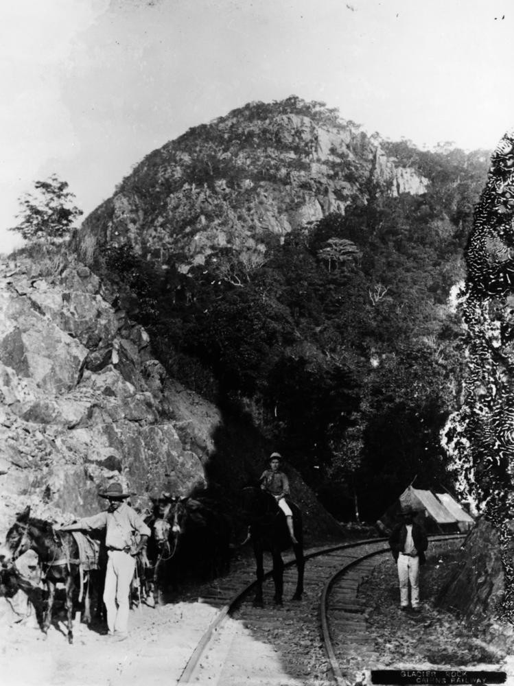 men with mules and horses stand on a bend on a railway line 