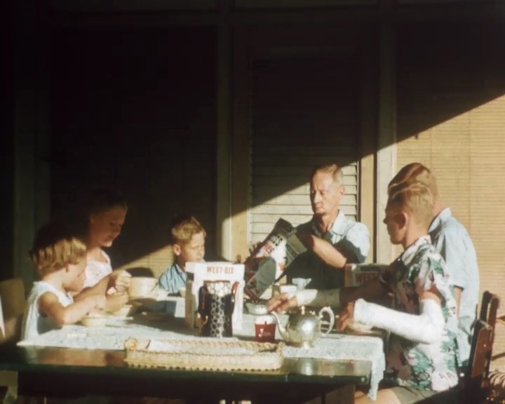 a family sits at a table for breakfast in the sun 