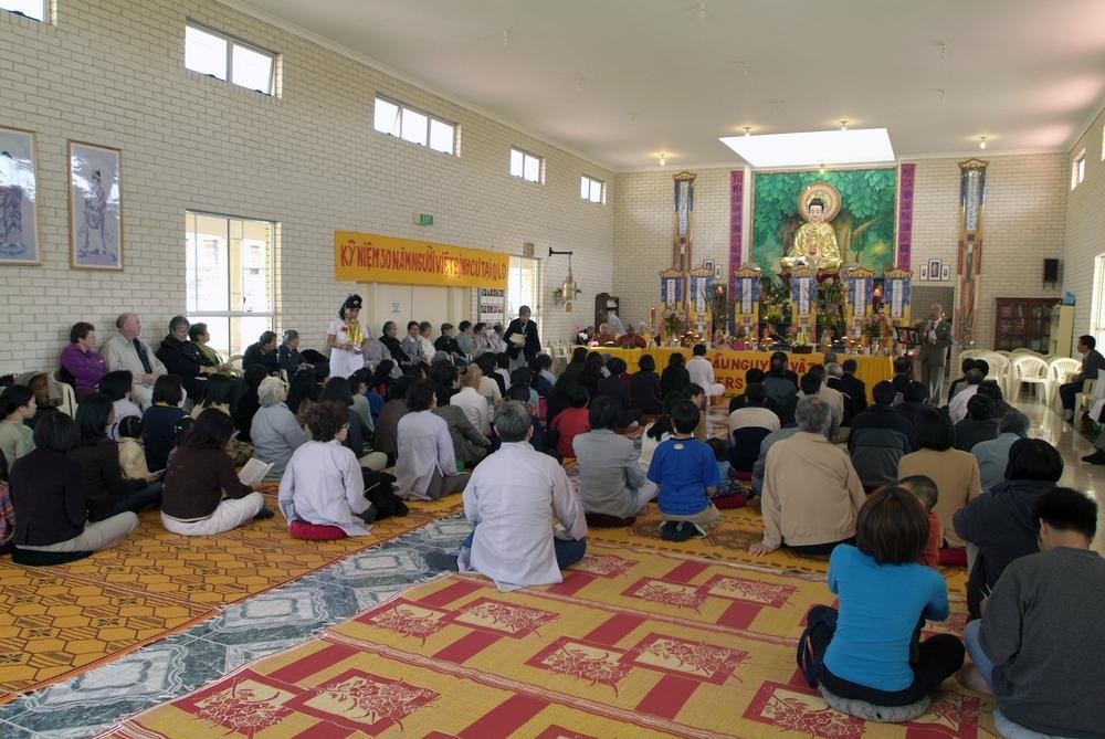 people sit on a carpet floor in a monastery