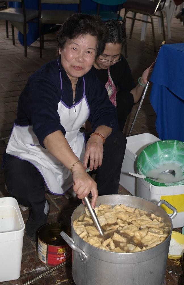 women prepare food in a large pot 