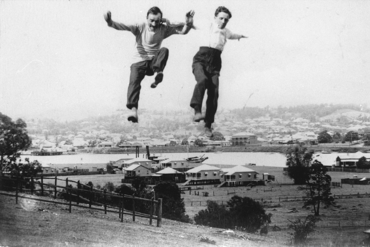 Two men jumping over city background