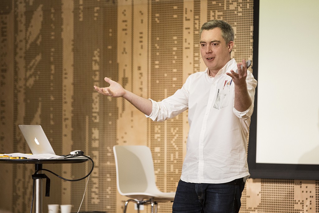 A man delivers a presentation gesturing broadly with his hands