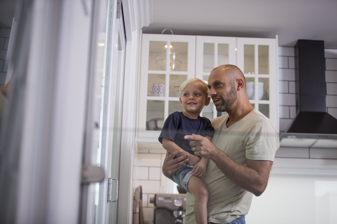 Man holding young child and looking and pointing to their right