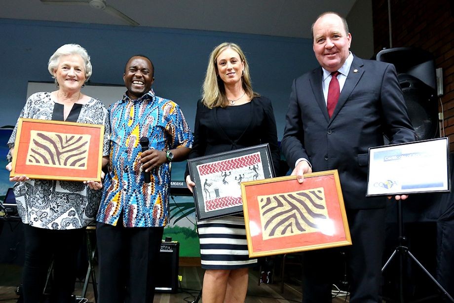 Rose Swadling Lawrence Chitura and Karen Morris show examples of art and Bruce Young MP holds a Certificate of Appreciation
