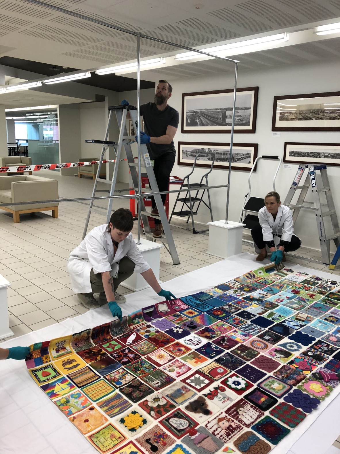 Preservation Services staff install the Quarantine Quilt on Level 1 at State Library