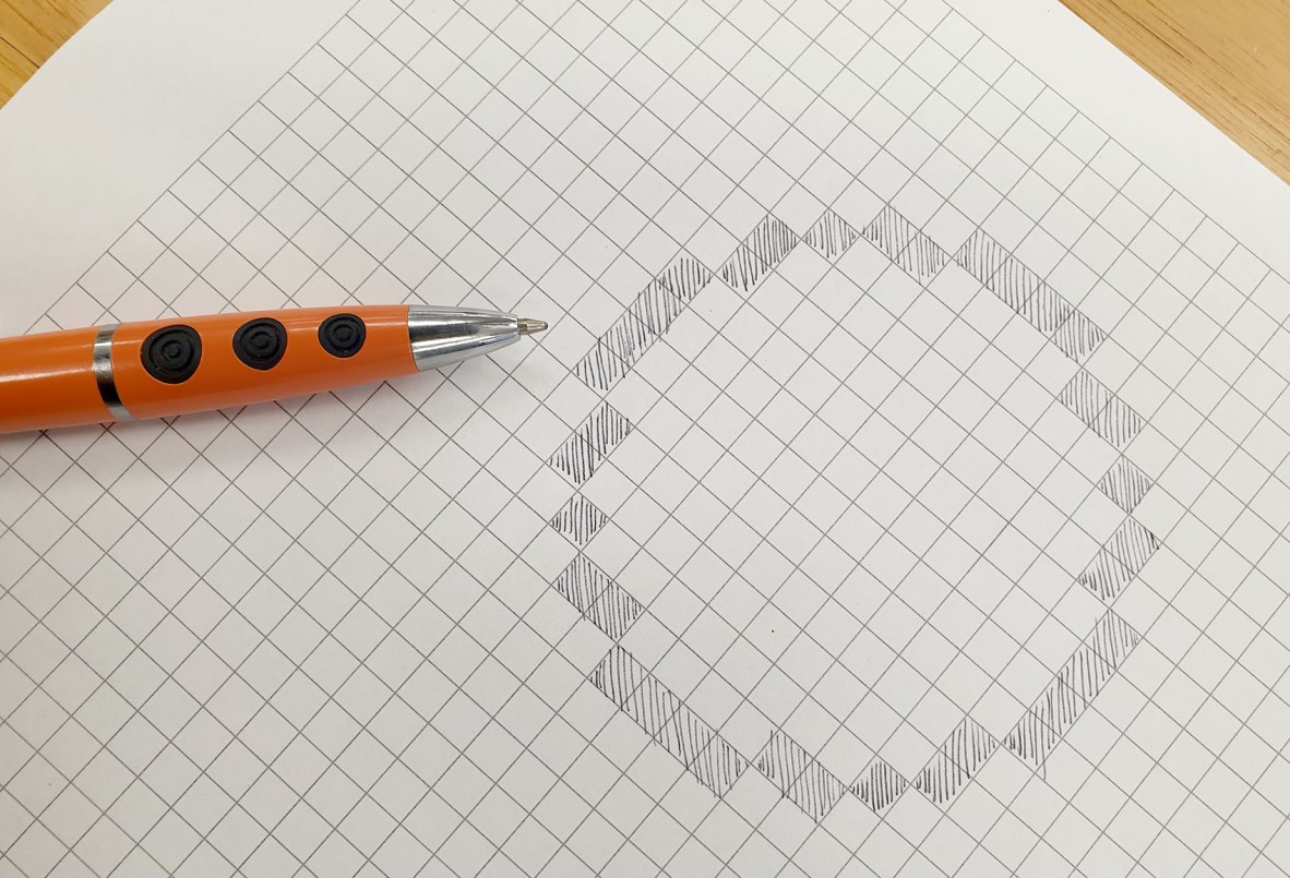 A photograph of a circle drawn on grid paper by colouring in squares.