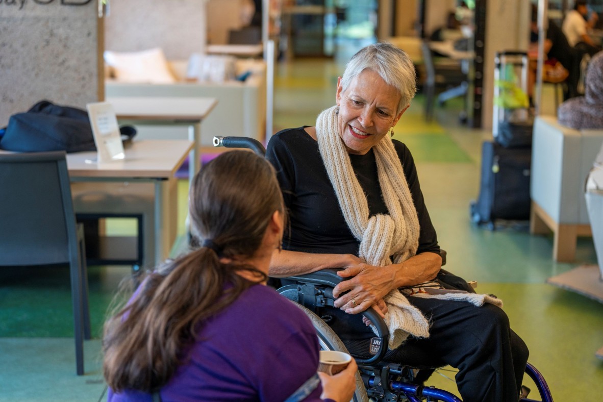 Lorraine is in a wheelchair and chats with an attendee