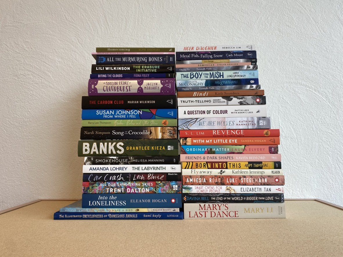 Two big stacks of books against a white wall all shortlisted titles in the 2021 Queensland Literary Awards
