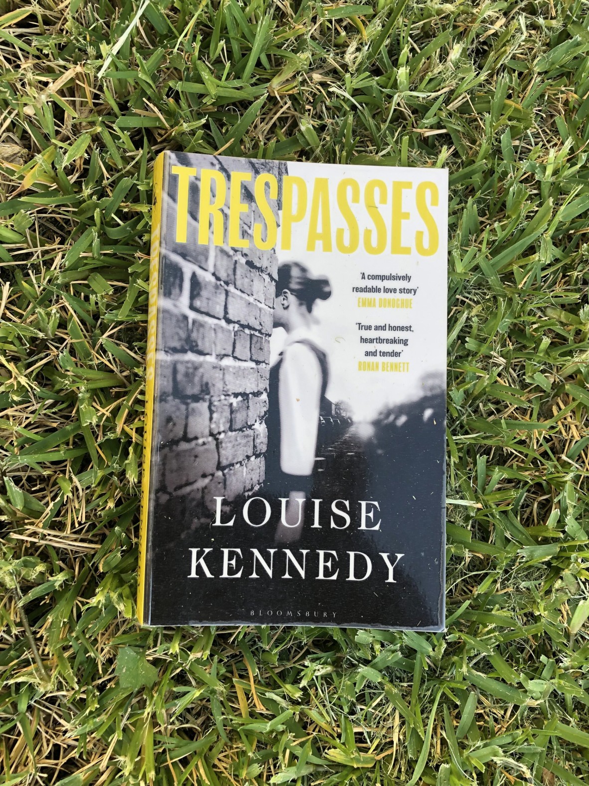 A copy of the book Trespasses by Louise Kennedy sits on a green lawn