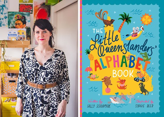 Sophie Beer stands in her work studio in a blue and white print dress; also shown is a copy of her book The Little Queenslanders' Alphabet Book, written by Sally Scudamore