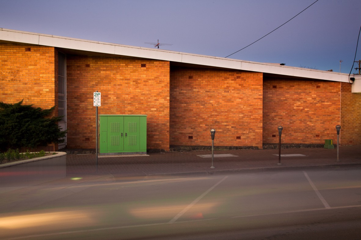 A brick building almost glows in the sunlight, contrasting with a dark sky.