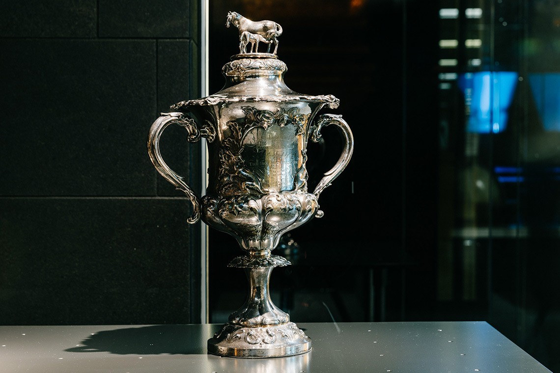 Sterling Silver Cup presented to Robert George Wyndham Herbert first Premier of Queensland whose horse won the Queensland Turf Clubs Corinthian Handicap Race  The cups cover features a modelled group of a horse and foal and the body of the cup is decorated with images of horses riders and kangaroos