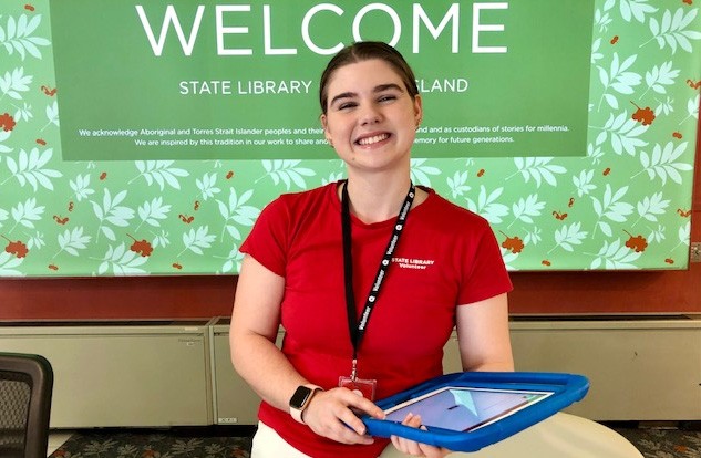 Smiling woman standing at State Library reception with an iPad.