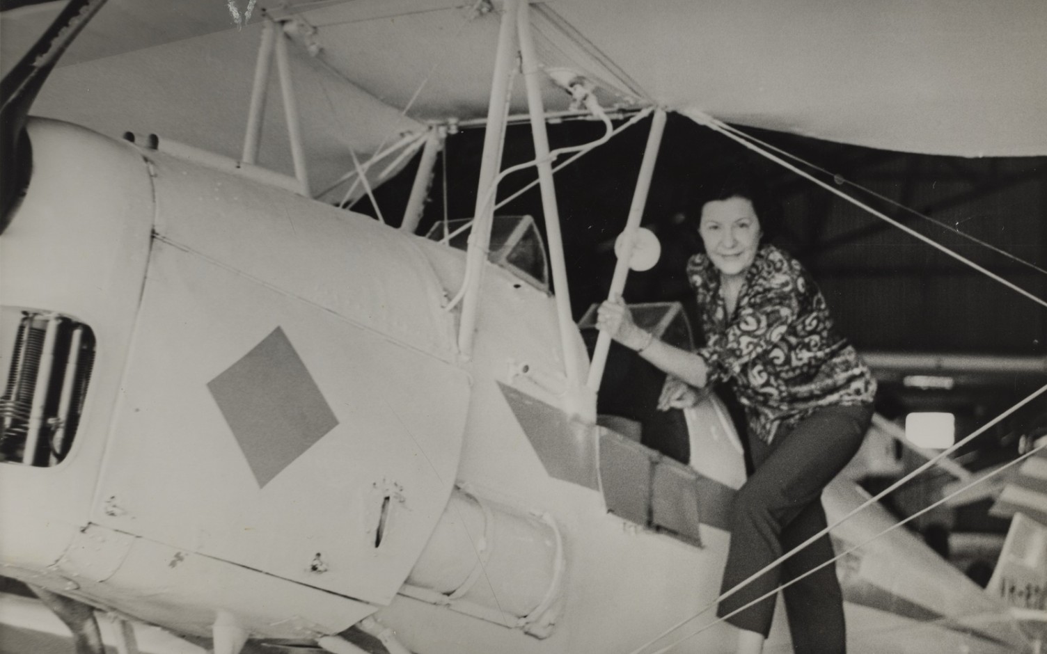 a woman is posing for a photo standing on the wing of a light aircraft